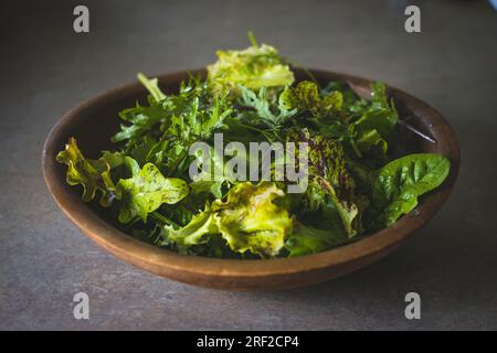 Gemischter grüner Salat aus biologischem Anbau in einer Holzschüssel Stockfoto