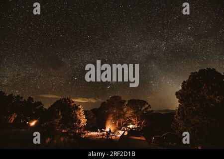 Ein Einzelgänger sitzt unter den Sternen und am Lagerfeuer auf dem Campingplatz in colorado Stockfoto