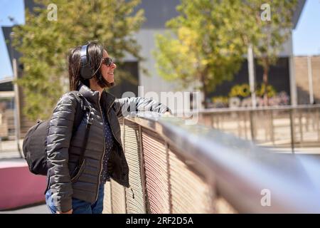 Lächelnde junge Frau, die Musik mit Kopfhörern hört Stockfoto