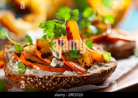 Offenes Sandwich mit gegrilltem Kürbis und Weichkäse auf mehrkörnigem Roggenbrot. Stockfoto