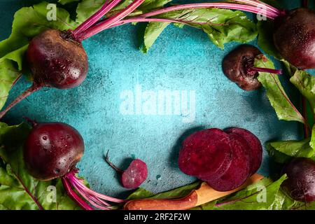 Frische biologische Rote Bete mit grünen Blättern auf blauem Hintergrund. Draufsicht, Kopierbereich. Stockfoto