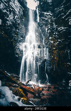 Der wunderschöne Burgbach-Wasserfall im Schwarzwald Deutschlands. Dieser Wasserfall fällt in ein weißes Schneetal Stockfoto