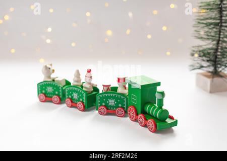 Grüner weihnachtszug, Tanne und verschwommene Bokeh-Lichter im Hintergrund. Frohe Weihnachten und frohe Neujahrskarte für die Winterferien. Stockfoto