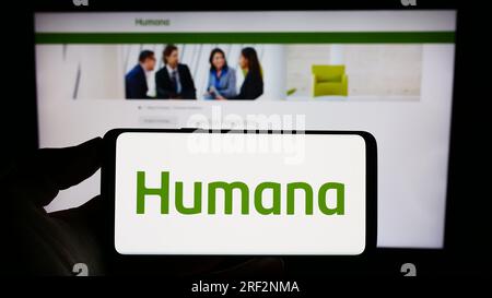 Person, die ein Mobiltelefon mit dem Logo der amerikanischen Krankenversicherung Humana Inc. Auf dem Bildschirm vor der Webseite hält. Konzentrieren Sie sich auf das Display des Telefons. Stockfoto