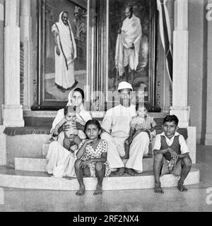 Altes schwarzweißes 1900er-jähriges Bild der indischen Familie Ehemann Ehefrau Kinder unter Kasturba Mahatma Gandhi Portrait Rajkot Gujarat India 1950er Stockfoto