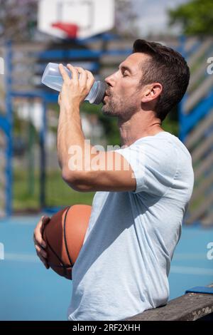 Junger Basketballspieler, der Wasser aus der Flasche trinkt Stockfoto