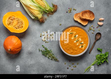 Hausgemachte Kürbiscreme-Suppe, grauer Betonhintergrund. Gemütliches Abendessen im Herbst. Blick von oben, flach liegend Stockfoto