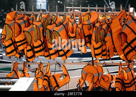 Die orangefarbene Schwimmweste ist eine Sicherheitsvorrichtung, die auf einem großen Tourboot an einem Stahlgeländer hängt Stockfoto