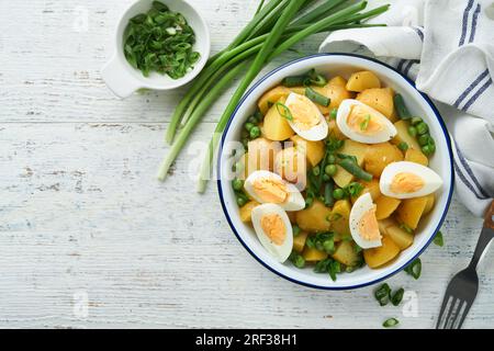 Traditioneller Kartoffelsalat mit Speck und Eiern in einer weißen Schüssel. Picknick-Food-Konzept. Schüssel mit warmem Kartoffelsalat. Deutscher Kartoffelsalat. Draufsicht. Stockfoto