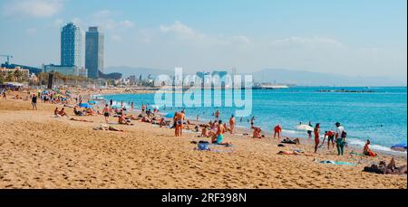 Barcelona, Spanien - 27. Juli 2023: Badende und Sonnenanbeter am Sant Sebastia Beach in Barcelona, Spanien, früh am Morgen eines Sommertags, und Hotel A Stockfoto