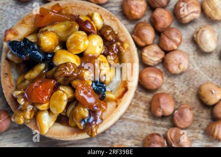 Kleine runde Törtchen mit verschiedenen Füllungen, knusprige Törtchen mit Haselnüssen, Erdnüssen und anderen Zutaten, Törtchen aus Teignüssen und getrockneten fru Stockfoto