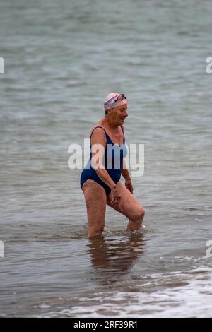 Eine ältere Dame, die aus dem Meer ging, nachdem sie im solent im kalten Wasser schwimmen war. Stockfoto