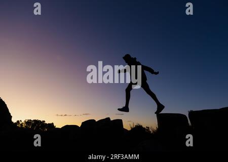 Junger Mann auf einer Wanderung mit Silhouette vor Sonnenuntergang Stockfoto