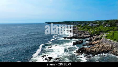 Aus der Vogelperspektive sehen Sie Wellen, die über Felsen in der Nähe des Margway-Laufpfads in Ogunquit, Maine, über den Ozean stürzen. Stockfoto