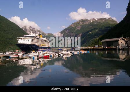 Englisches Kreuzfahrtschiff legte im Geiranger-Dorf in Geiranger Fjord an einem schönen Juli-Tag mit Motorbooten an der Anlegestelle in Norwegen Europe fest Stockfoto