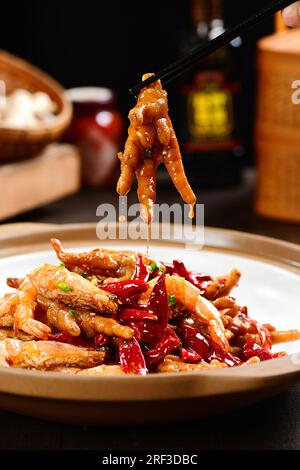 Hähnchenfüße mit heißem Pfeffer auf dunklem Retro-Hintergrund. Köstliches und einzigartiges chinesisches Essen. Stockfoto