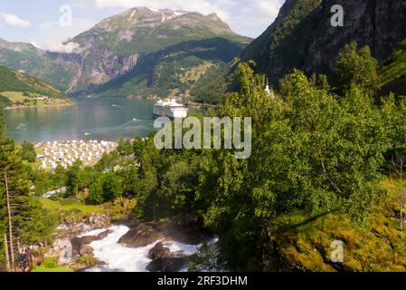 Sehen Sie den mächtigen Storfossen-Wasserfall hinunter zum Geiranger Fjord, der von baumbedeckten Berggipfeln umgeben ist, über 35m m vom Hotel Union durch das Dorf Geiranger Stockfoto