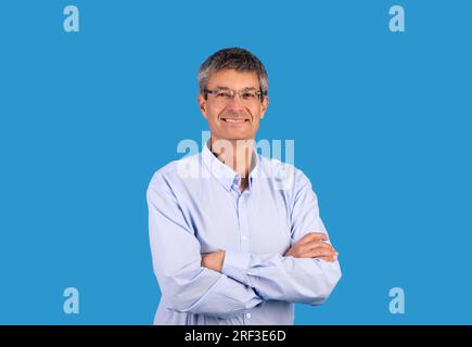 Glücklicher, reifer Geschäftsmann im Hemd, der sich quer durch die Hände posiert, Studiofoto Stockfoto