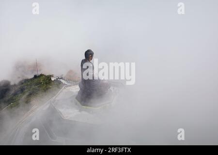 Bronzestatue Buddha auf dem Gipfel des Berges Fansipan im geheimnisvollen Nebel. Provinz Lao Cai, Vietnam Stockfoto
