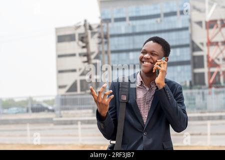 Ein junger afrikaner, der zur Arbeit geht und telefoniert Stockfoto