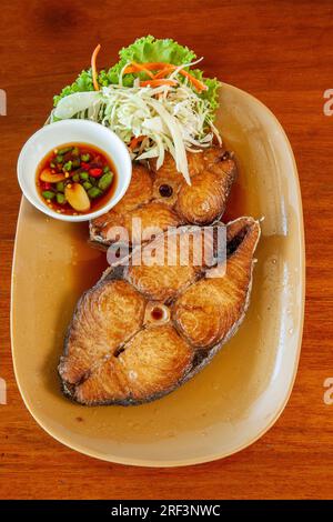 Frittierte Makrele mit Fischsauce auf Teller mit Holztisch, thailändische Meeresfrüchte, Stockfoto