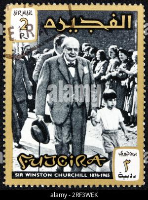 FUJEIRA - CA. 1966: Ein in Fujeira gedruckter Stempel zeigt Sir Winston Spencer Churchill mit Enkel Nicholas Soames, ca. 1966 Stockfoto