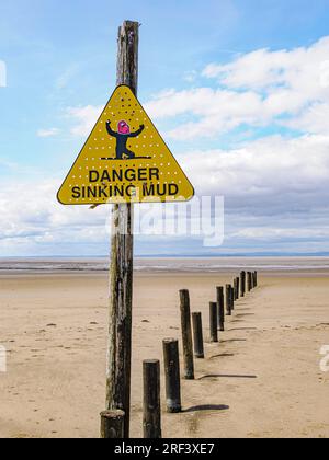 Warndreieck am Strand von Weston super Mare in Somerset mit einem Comic-Gesicht, um vor sinkendem Schlamm zu warnen Stockfoto