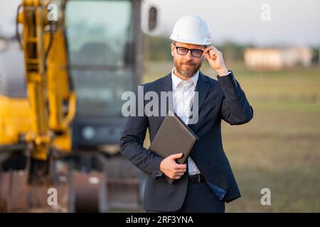 Buider-Mann in Anzug und Schutzhelm. Bauinvestor. Geschäftsmann-Investor vor der Baustelle. Erfolgreicher Investor. Ein hübscher Mann im Anzug Stockfoto
