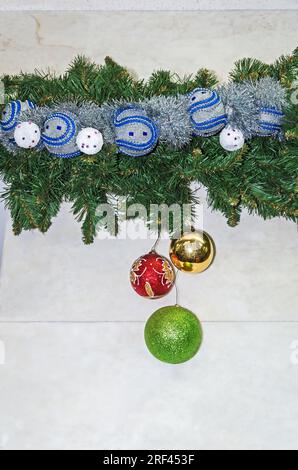An den Marmorwänden hängt eine Längsschleife aus Lametta, Kugeln, Glitzern und anderen Weihnachtsdekorationen Stockfoto