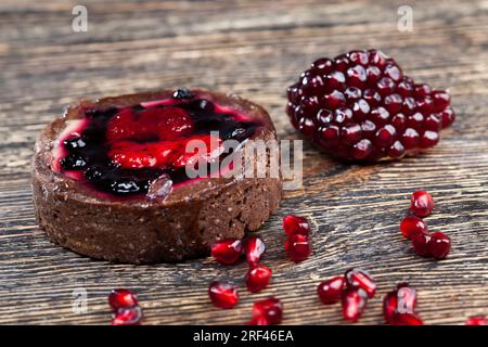 Dessert aus gebackenen Törtchen, Schokoladentörtchen mit Obst- und Beerenfüllung, runden Törtchen mit Erdbeeren und Blaubeeren in Buttercreme, Nahaufnahme Stockfoto