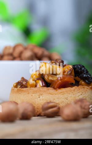 Knusprige Törtchen mit Haselnüssen, Erdnüssen und anderen Zutaten, Weizentörtchen mit Nüssen und getrockneten Früchten in Sahne-Karamell, Weizentörtchen mit Pfeffer Stockfoto