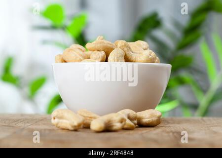 Knusprige Cashewnüsse in einer Schüssel, köstliche und gesunde rohe Cashewnüsse auf einem Teller, Nahaufnahme von geschälten Cashews auf dem Küchentisch in einer Glasplatte Stockfoto