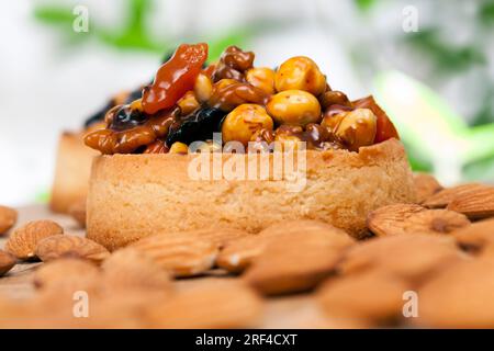 Kleine runde Törtchen mit verschiedenen Füllungen, knusprige Törtchen mit Haselnüssen, Erdnüssen und anderen Zutaten, Teig Törtelnüsse und getrocknete Obstbucht Stockfoto