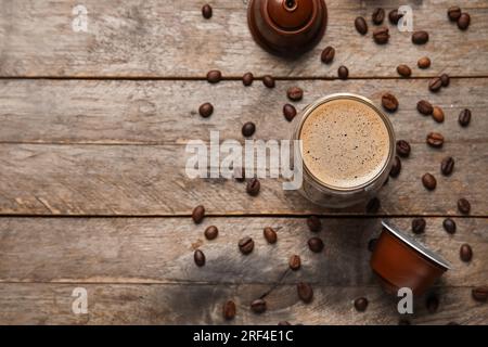Ein Glas köstlicher Kaffee, Pads und Bohnen auf einem Holztisch Stockfoto