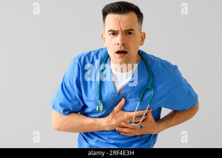 Männlicher Arzt mit Herzinfarkt auf hellem Hintergrund Stockfoto