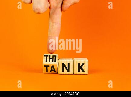 Denkfabriksymbol. Ein Geschäftsmann dreht Holzwürfel um und ändert das Wort „Tank“, um zu denken, oder umgekehrt. Wunderschöner orangefarbener Tischhintergrund, Kopie Spa Stockfoto