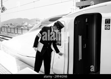 Takeo Onsen, Präfektur Saga, Japan. 11. März 2023. Ein Schaffner bereitet sich auf die Abfahrt mit dem neuen Hochgeschwindigkeitszug Nishi-Kyushu Shinkansen (è ¥¿ä¹å·žæ-°å¹¹ç·š) vor, der Hochgeschwindigkeitszüge von Takeo-Onsen nach Nagasaki anbietet und von der Eisenbahngesellschaft Kyushu (JR Kyushu JRä¹å·ž) betrieben wird.aufgrund von Einwänden der örtlichen Präfekturregierung Saga Der Service verkehrt nicht direkt zum Bahnhof Hakata in Fukuoka und ist über einen langsameren Expresszug „Relay Kamome“ mit dem nationalen Shinkansen-Netz verbunden, der mit dem Zug „Kamome“ N700S fährt. Intercity-Passagiere müssen einen plattformübergreifenden Transfer machen Stockfoto