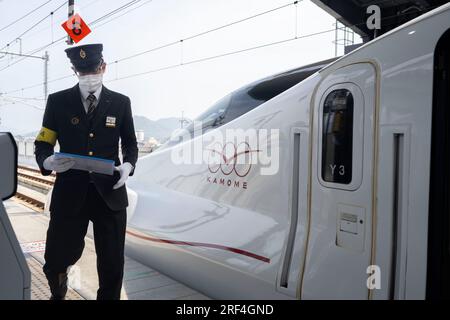 Takeo Onsen, Präfektur Saga, Japan. 11. März 2023. Ein Schaffner bereitet sich auf die Abfahrt mit dem neuen Hochgeschwindigkeitszug Nishi-Kyushu Shinkansen (è ¥¿ä¹å·žæ-°å¹¹ç·š) vor, der Hochgeschwindigkeitszüge von Takeo-Onsen nach Nagasaki anbietet und von der Eisenbahngesellschaft Kyushu (JR Kyushu JRä¹å·ž) betrieben wird.aufgrund von Einwänden der örtlichen Präfekturregierung Saga Der Service verkehrt nicht direkt zum Bahnhof Hakata in Fukuoka und ist über einen langsameren Expresszug „Relay Kamome“ mit dem nationalen Shinkansen-Netz verbunden, der mit dem Zug „Kamome“ N700S fährt. Intercity-Passagiere müssen einen plattformübergreifenden Transfer machen Stockfoto