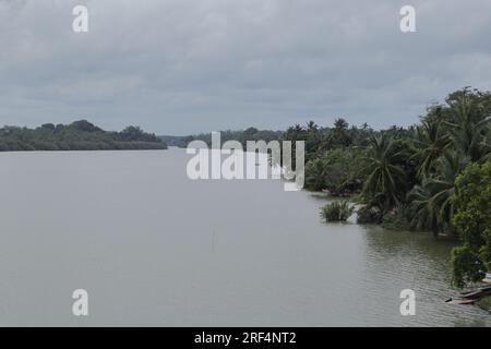 Kalutara, Sri Lanka - 15. 2023. Juli - Blick aus dem hohen Winkel auf den Schwarzen Fluss mit einem kleinen Boot, das in Richtung Uferseite segelt Stockfoto