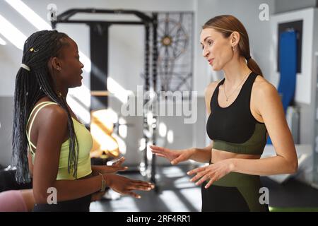Zwei sportliche Frauen, die sich in einem Fitnessraum unterhalten. Sportkonzept. Stockfoto