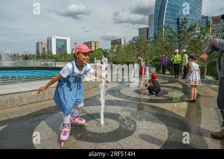 Kinder, die im Brunnen auf dem Sukhbaatar Square oder Dschingis Khan Square spielen, auch Chingis Khan Square genannt, im Zentrum von Ulaanbaatar in der Mongolei. Stockfoto