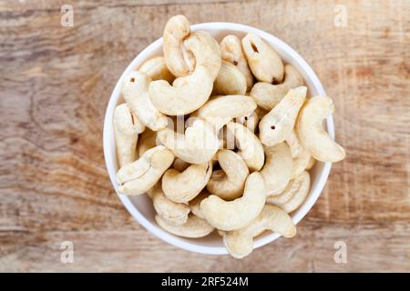 Knusprige Cashewnüsse in einer Schüssel, köstliche und gesunde rohe Cashewnüsse auf einem Teller, Nahaufnahme von geschälten Cashews auf dem Küchentisch in einer Glasplatte Stockfoto