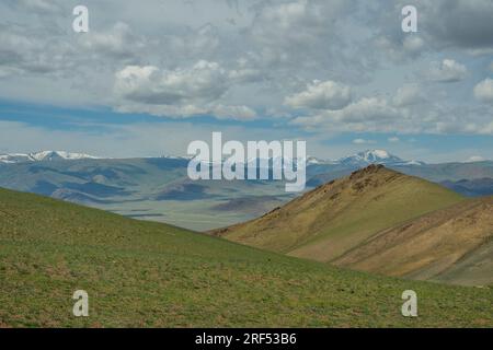 Blick von einem Bergpass auf die trockene, felsige Landschaft mit schneebedeckten Altai-Bergen (Altay-Berge) in der Nähe von Ulgii in der Bayan-Ulgii-Provinz in We Stockfoto