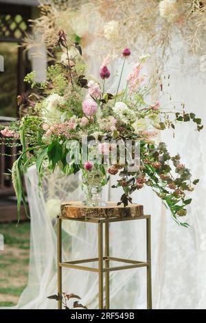 Die Braut hält ihren Brautstrauß mit roten Pfingstrosen und Sonnenblumen in den Händen. Stockfoto