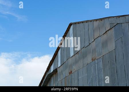 Verwitterte Scheune mit Wellblechverkleidungen am blauen Himmel Stockfoto