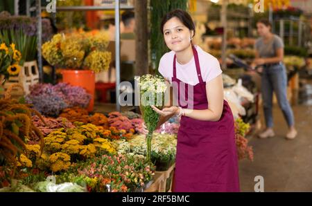 Porträt einer positiven Blumenmarktverkäuferin mit Gänseblümchen für Käufer Stockfoto