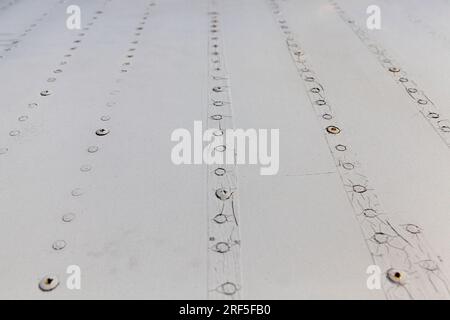 Aluminiumbleche, die durch Schweißen und Nieten miteinander verbunden werden, Nahaufnahme eines Teils der Außenhaut des Flugzeugrahmens Stockfoto