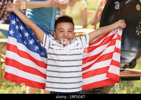 4. Juli - Unabhängigkeitstag Amerikas. Die Familie macht ein Picknick im Park. Glücklicher kleiner Junge mit der Nationalflagge der Vereinigten Staaten Stockfoto