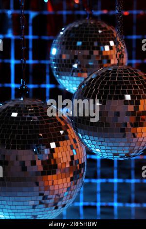 Glänzende Disco-Bälle gegen einen Partyvorhang unter farbigen Lichtern Stockfoto