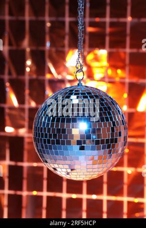 Glänzende Discokugel gegen eine Folienparty unter farbigen Lichtern Stockfoto
